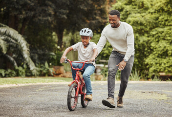 Black family, father teaching child cycling in park with bicycle and helmet for safety, learning and help. Support, motivation and trust, man with boy outdoor and learn bike riding with mockup space
