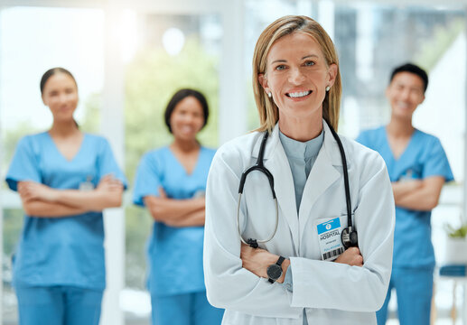 Portrait, team and a doctor woman arms crossed, standing in the hospital for healthcare or medicine. Leadership, medical or teamwork with a mature female health professional in a clinic for treatment