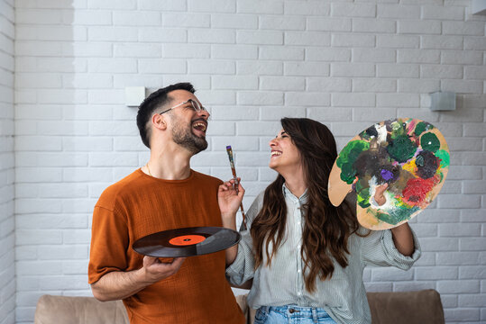 Creative couple painting on canvas in art studio. Modern artwork paint, creative, contemporary and successful fine art artist portrait with boyfriend holding LP as musician