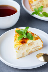 Cottage cheese casserole with an apple and a cup of tea on a gray table. Cottage cheese casserole
