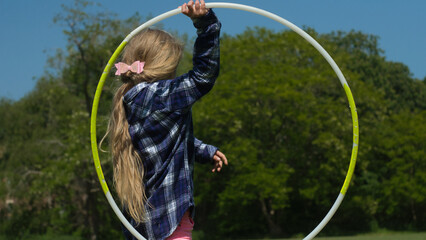 Girl with blonde hair playing with hula hoop