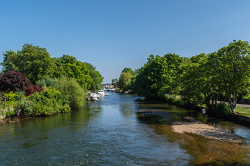 Fototapeta na wymiar Christchurch, UK - June 1st 2023: The tree lined riverbanks of the River Avon.