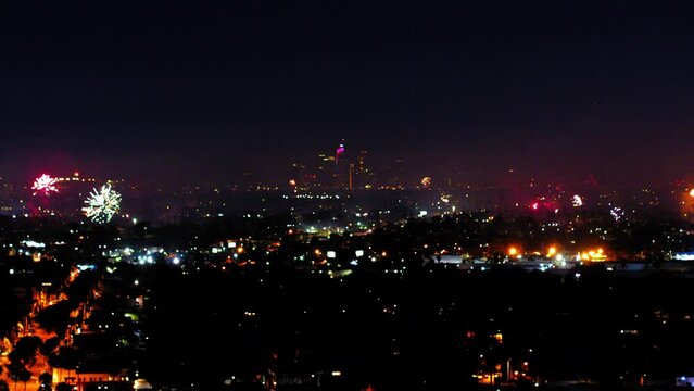 Aerial Panning Shot Of Illuminated City With Firework Explosion At Night, Drone Flying Over Cityscape Against Sky - Los Angeles, California