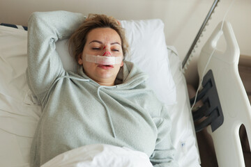 A woman lies in the hospital with a nose injury