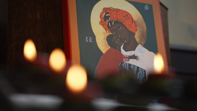 Black Madonna and child with flickering candles.
An image of a black Mary with a baby Jesus. Candles in the foreground.