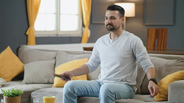 Successful mobile banking online payment guy credit card app. Satisfied man relax on sofa with hands behind head at home after a successful online payment internet order