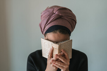 Young jewish woman with a covered head prays with a siddur (jewish prayer book) in her hands, covered his face with her hands (66)