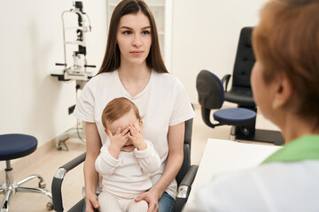 Young mother with infant at ophthalmologist appointment