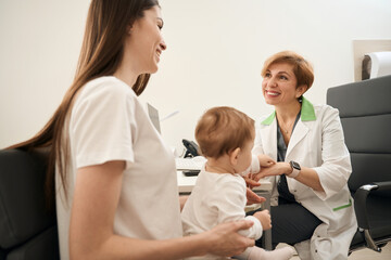 Friendly eye doctor providing initial consultation to female parent with baby