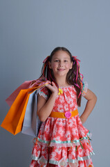 Menina com vestido de festa junina  sorridente com sacolas de compras 