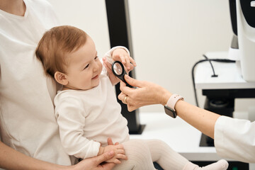 Experienced pediatric ophthalmologist examining baby eyes during consultation
