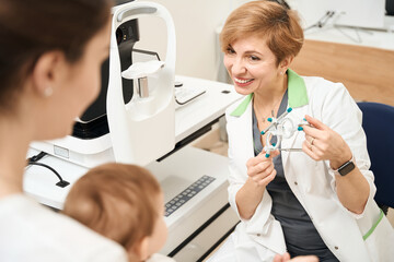 Oculist demonstrating ophthalmic device to baby before eyesight examination