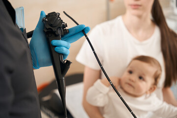 Expert endoscopist preparing infant for endoscopy procedure in mother presence