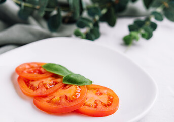 Sliced red tomatoes and basil leaves