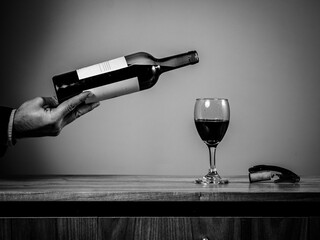 Hombre elegante sirviendo vino en una copa, en fotografía en blanco y negro