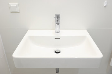 Modern white sink near light wall in bathroom