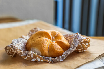 Serviette with Kaiser roll on parchment paper, closeup