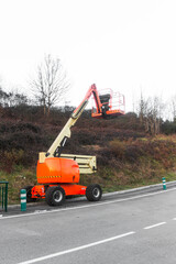 orange and light yellow mobile telescopic crane in on a road on an autumn day, Crane to do electric post checking operations
