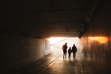 silhouettes of a family in a subway tunnel taking an enjoyment walk all together on a sunny summer...