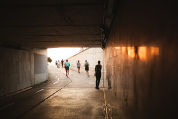 silhouettes of people walking and doing sports activities through a tunnel, tunnel with sunlight...