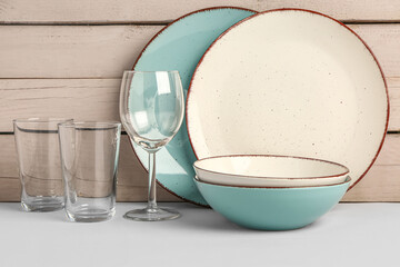 Set of different dishes on table near white wooden wall