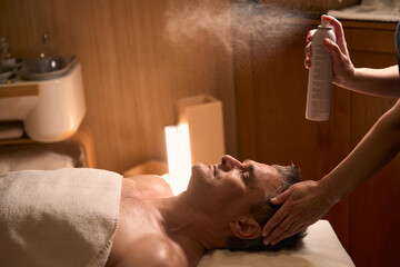 Experienced spa salon beautician hydrating client skin