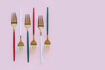 Golden forks on pink background
