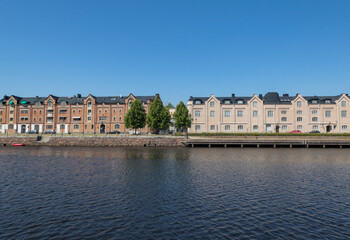 View of buildings by river against clear blue sky