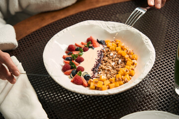 Woman eating breakfast fruit cereal at table