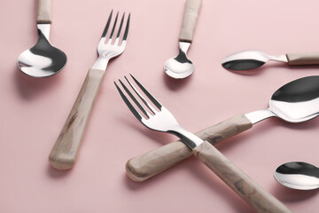 Stylish forks and spoons on pink background