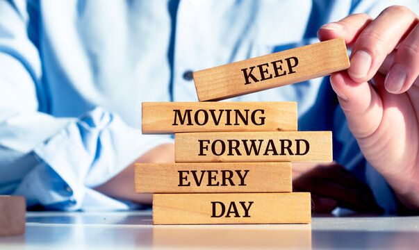 Close up on businessman holding a wooden block with a "Keep moving forward every day" message