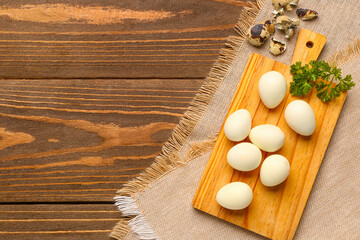 Board of boiled quail eggs with shells on wooden background