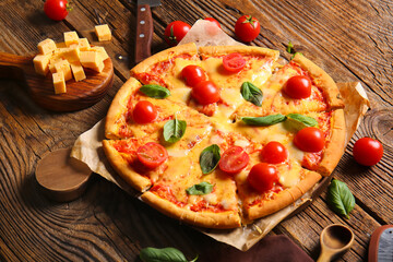 Baking paper with tasty pizza margarita on wooden table