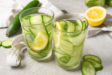 Glasses of infused water with cucumber slices on grey table