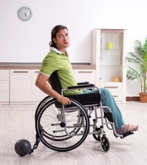 Young male invalid in wheel-chair suffering at home