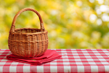 Empty wicker basket on a red checkered tablecloth. Autumn background. Free space for collage - 609392577
