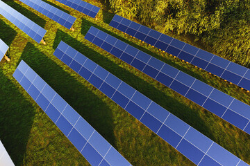 Solar panels aerial view among green trees in the forest at sunset
