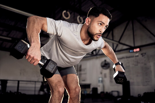 Fitness, dumbbells and man exercise at gym for training workout with focus. Serious male athlete or bodybuilder with weights for strong muscle, power or motivation for hard work and bent over row