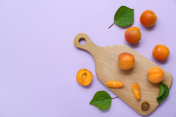 Board with fresh apricots and leaves on lilac background