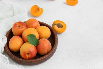Plate with fresh apricots on white table