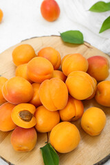 Board with fresh apricots and leaves on white background