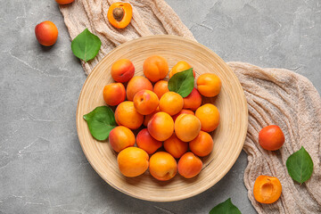 Plate with fresh apricots on grey background