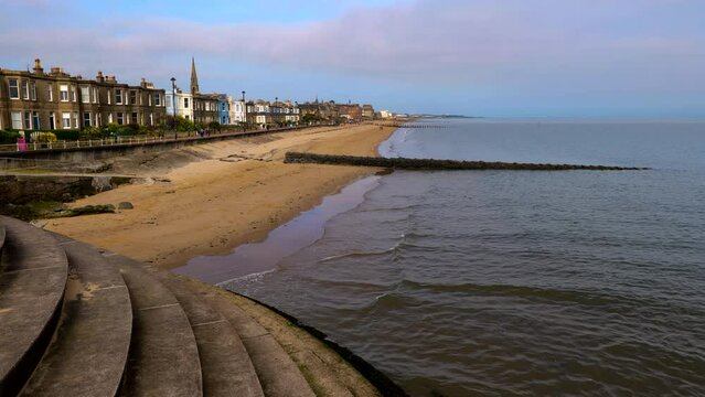 Beach in Portobello, coastal suburb in city of Edinburgh, Scotland, UK. View from promenade viewpoint with stairs to the sea and skyline of seaside houses.