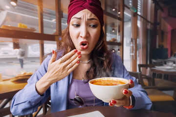 Indian woman tries a spicy and hot Tom Yam soup in a thai cuisine restaurant and reacts funny...