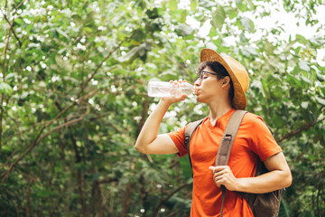Fototapeta premium Thirsty man drinking water while hiking by forest.