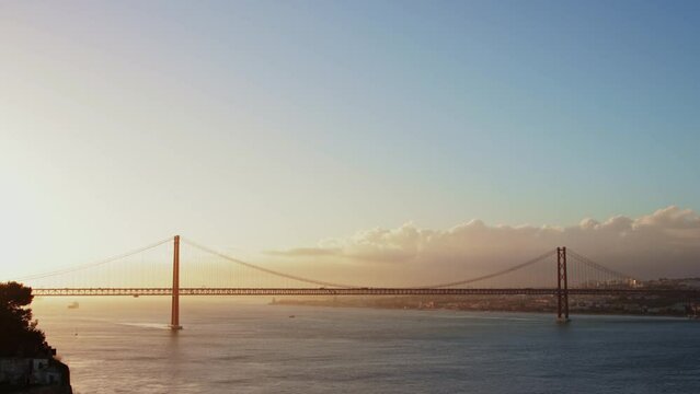 Sunrise over river and large suspension bridge