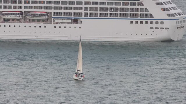 A sailing boat in front of a cruise ship