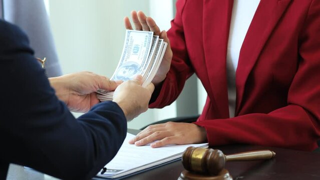 Business man raised her hand to deny accepting a bribe from a business partner, a brown envelope containing a large number of dollar bills as money for bribery, a corruption concept.