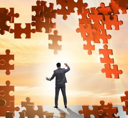 Businessman breaking the wall of jigsaw puzzle