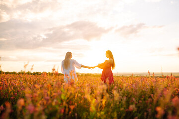 Portrait of a two beautiful  woman posing in a field with flowers.  Nature, vacation, relax and lifestyle. Summer landscape.